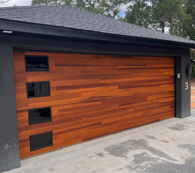 Modern wooden garage door with horizontal panels and small windows.
